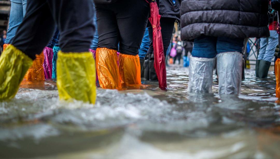 People walking through ankle-deep water with shoe protectors on