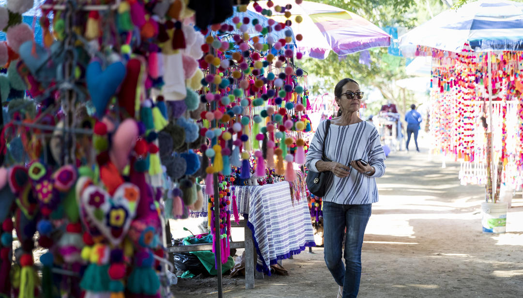 Middle-aged woman walking through art market and looking at colorful merchandise, Sayulita, Mexico