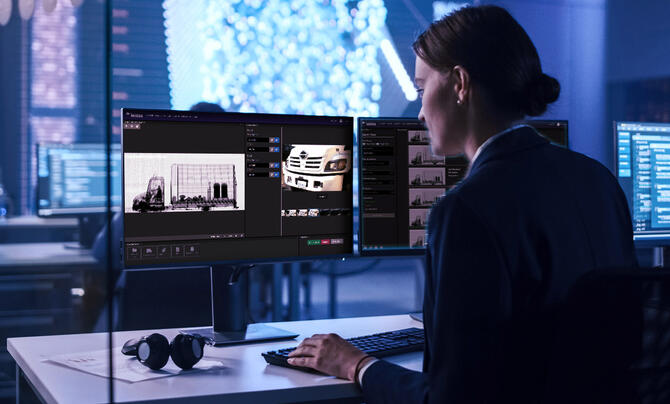 A security analyst reviews vehicle scan images and data on multiple monitors in a high-tech screening and inspection environment.