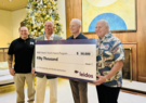 Four men holding an oversized check for $50,000.