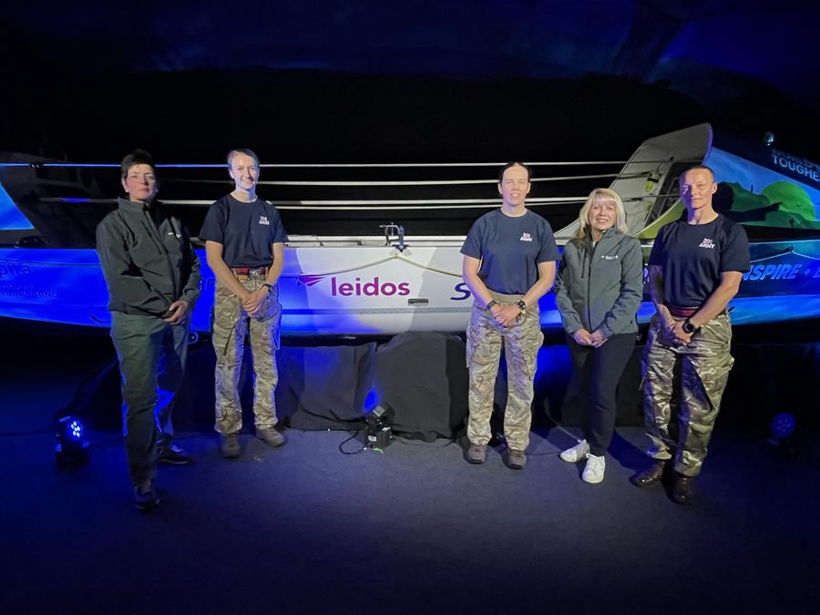 five people stand in front of a boat