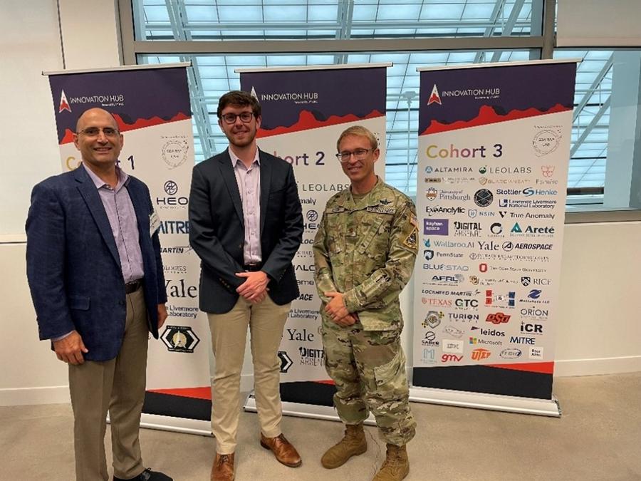 three men standing in front of 3 pop-up banners