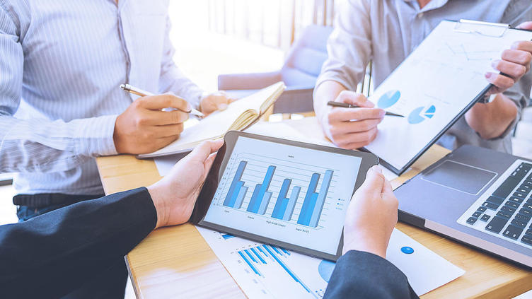 Meeting attendees looking at multiple graphs on table