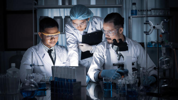 Three doctors collaborating in a darkened lab space