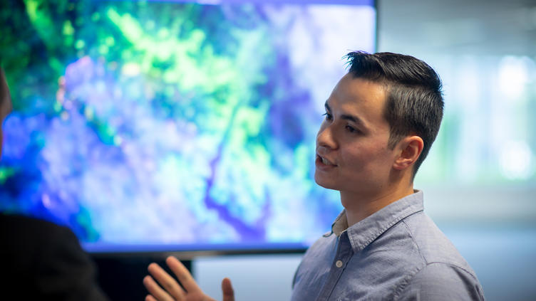 Asian male discussing map behind him